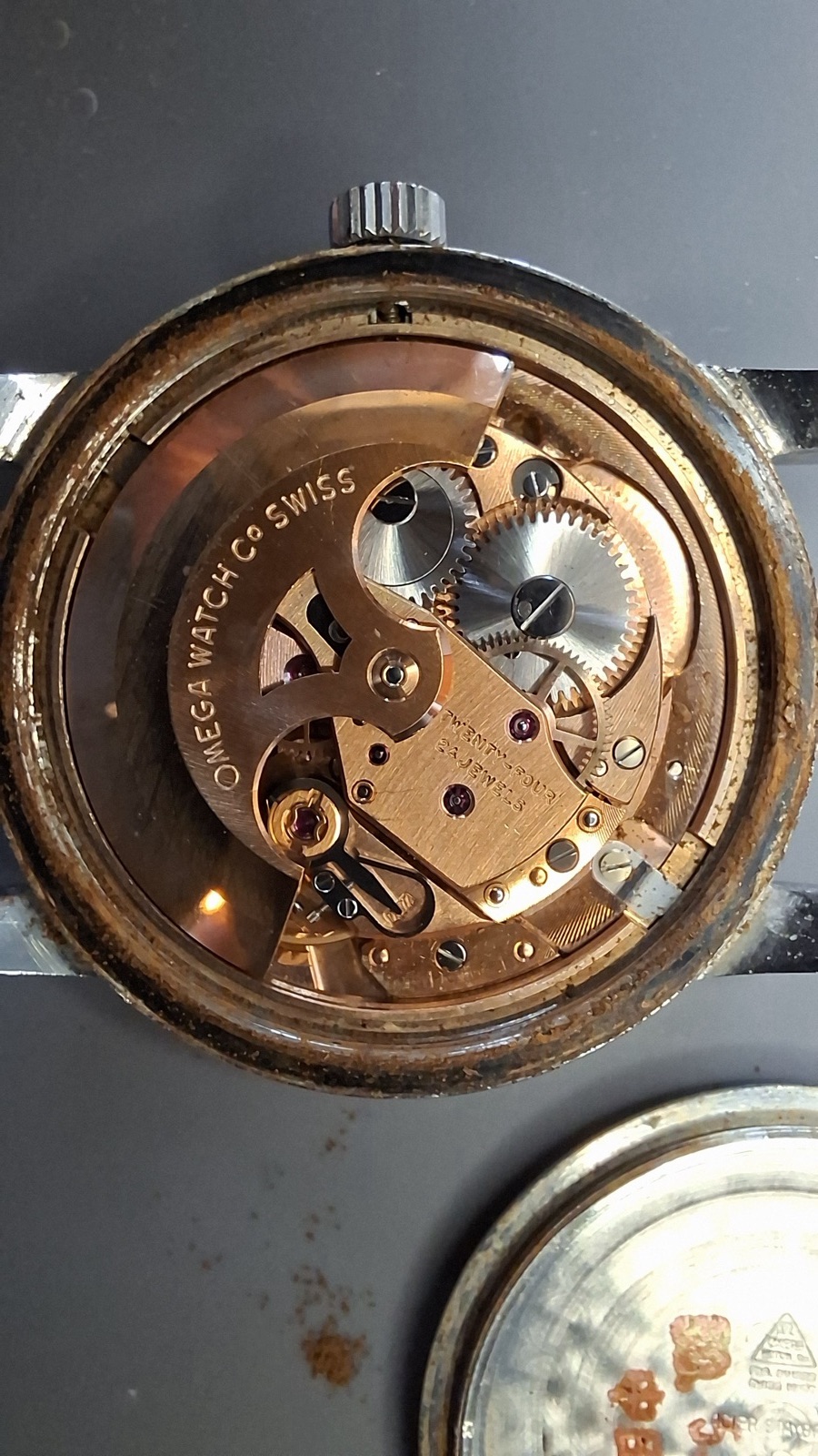 Opened Omega case showing rust around the rim